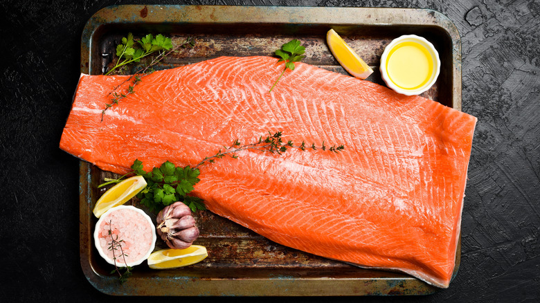 A side of raw salmon surrounded by seasonings.