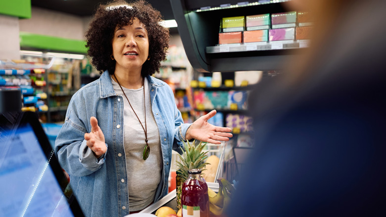 Unhappy grocery store customer complaining to grocery clerk