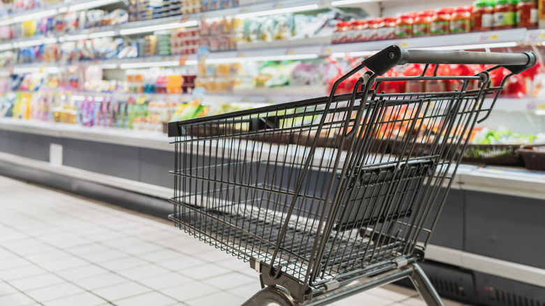 An empty shopping cart sits in a grocery store.