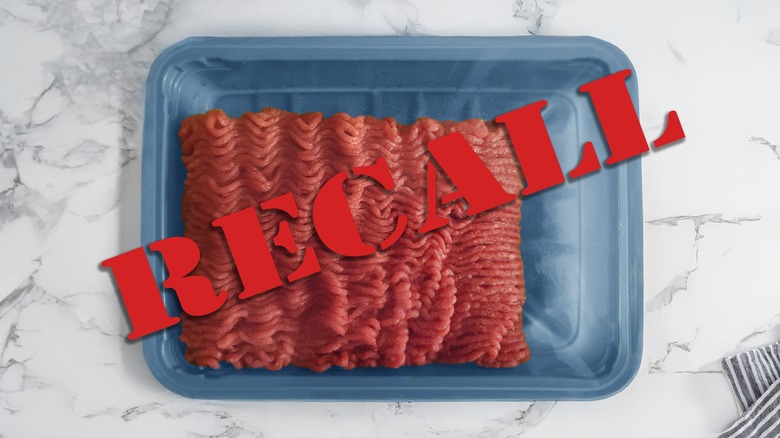Recall tag displayed over a package of ground beef on a marble counter