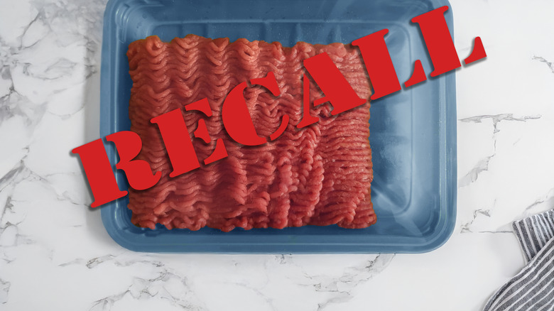 Recall tag displayed over a package of ground beef on a marble counter