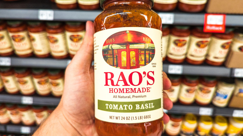 A hand holding Rao's sauce at a store.