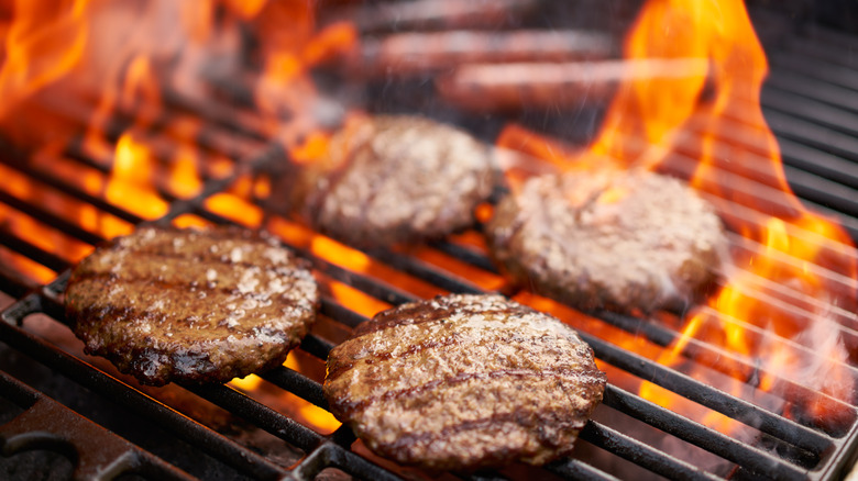 Burgers and hot dogs cooking on grill.