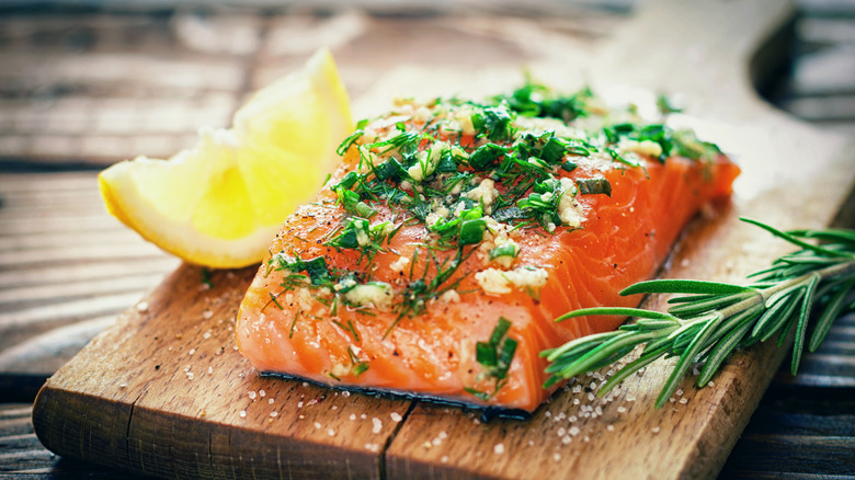 Raw salmon on cutting board with herbs