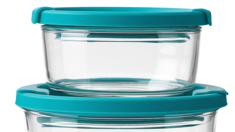 A glass container with a teal lid sits on top of a bigger container