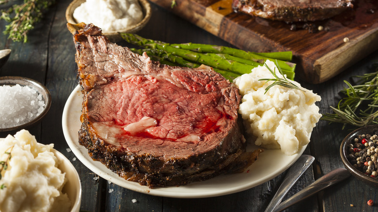 Prime rib on a plate with mashed potatoes and asparagus