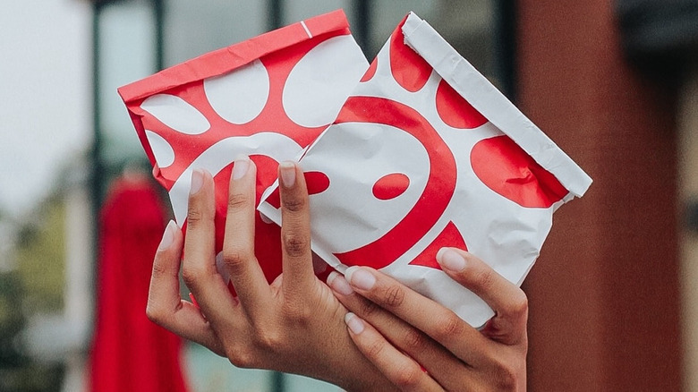 Someone holds two bags of Chick-fil-A sandwiches.