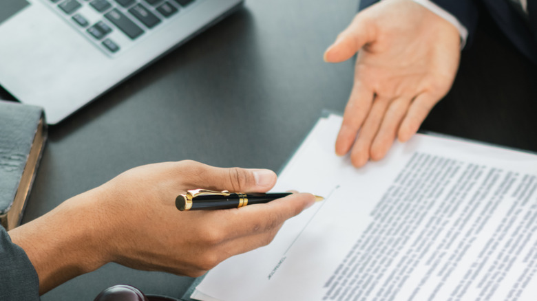 A hand holding a pen prepares to sign a contract.