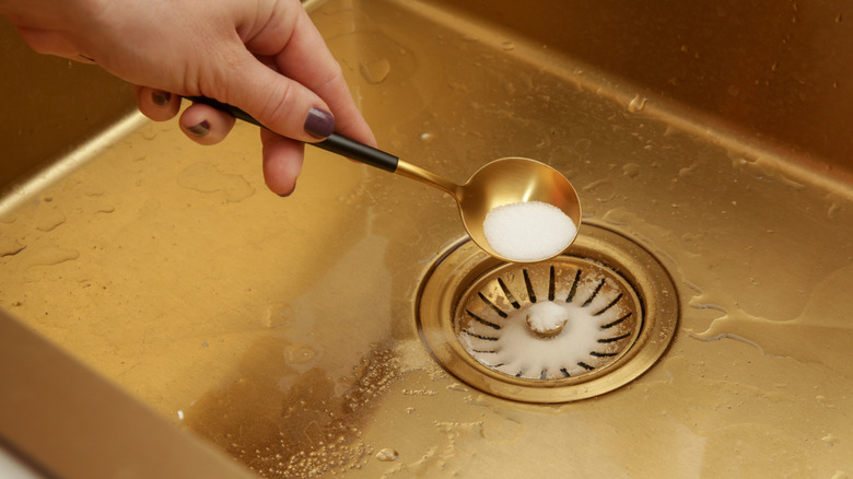 Sprinkling baking soda down the kitchen sink drain.