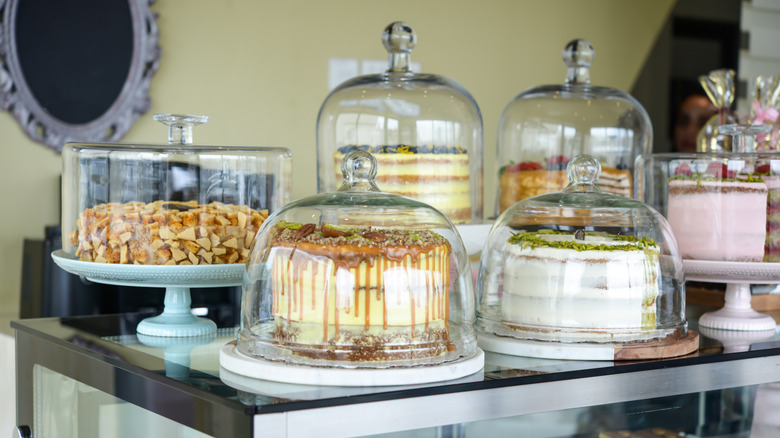 A series of different cakes under glass cake domes