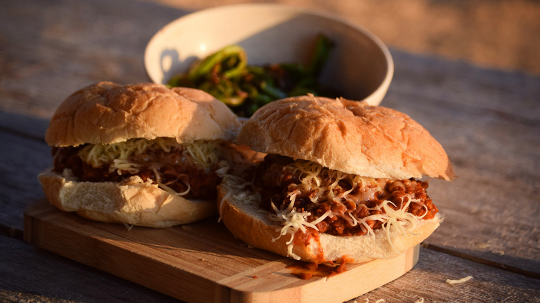 Two vegan sloppy joe sandwiches full of lentils on a wooden cutting board