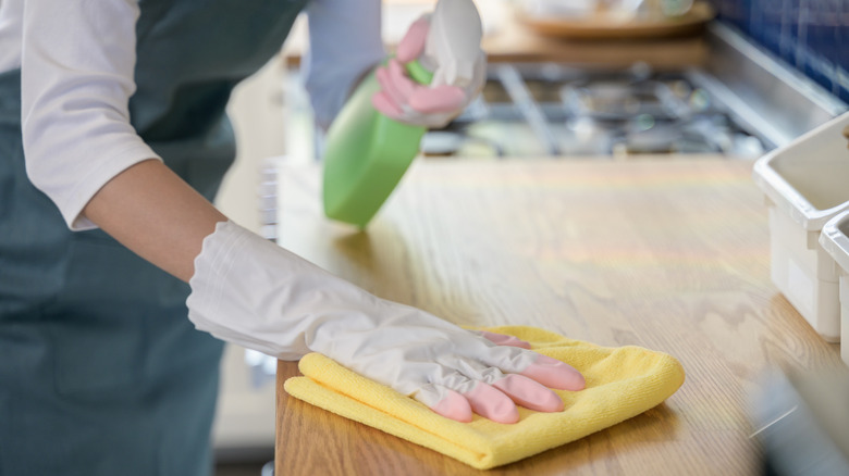 A hand using a cloth to clean a kitchen counter