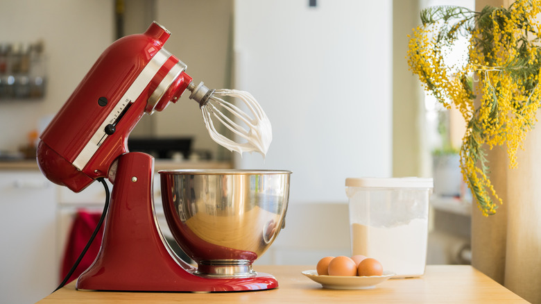 A red KitchenAid stand mixer makes whipped cream.