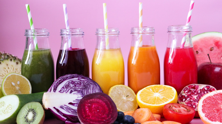 bottles of different juices on pink background