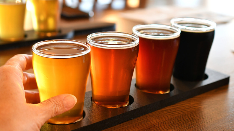 A hand picks up a beer from a flight
