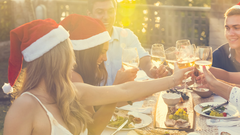 People with Santa hats on cheers with wine