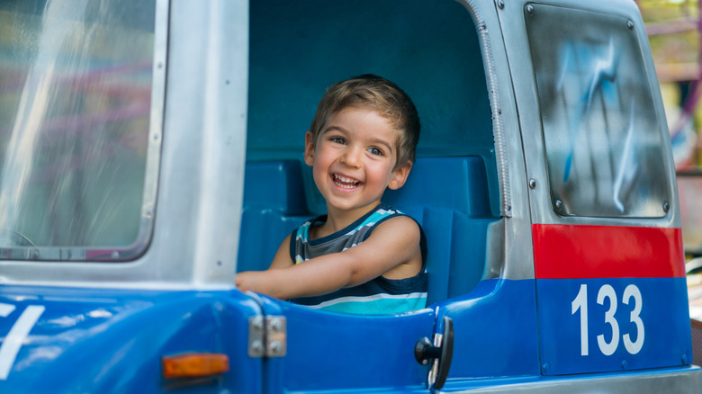A smiling child rides inside a coin-operated kiddie ride.