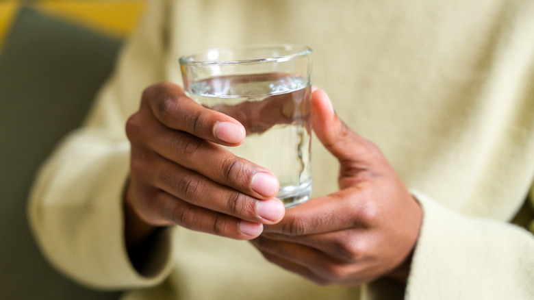 Two hands hold a glass of water.