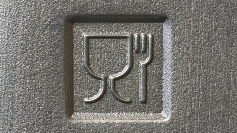 A fork and wine glass symbol is stamped into the bottom of a Styrofoam container.