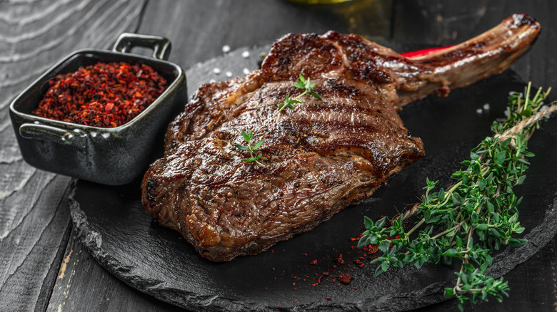 A bone-in ribeye cut steak with herbs and seasonings
