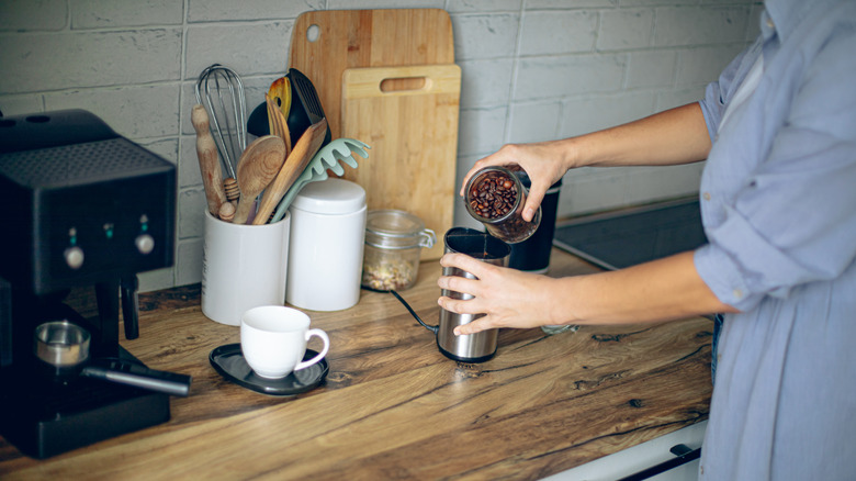 person grinding coffee beans for coffee