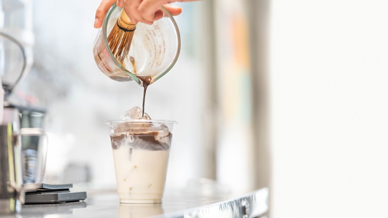 Person making iced hojicha latte