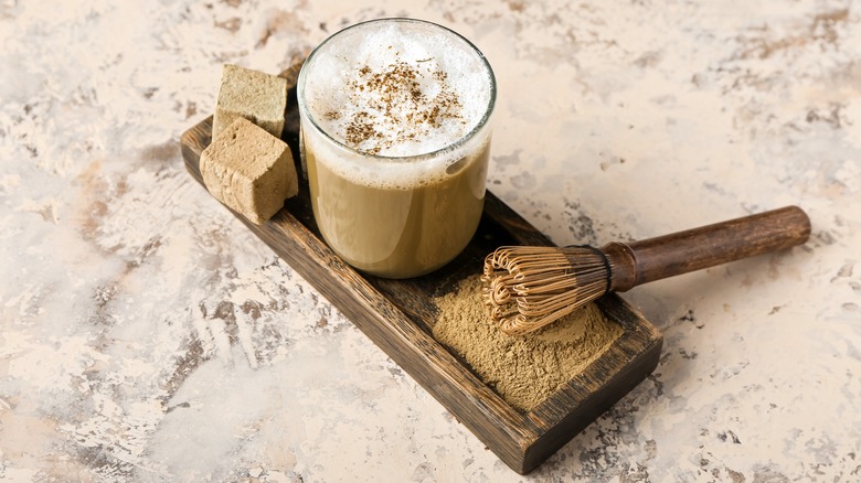 Hojicha latte with hojicha powder and a whisk