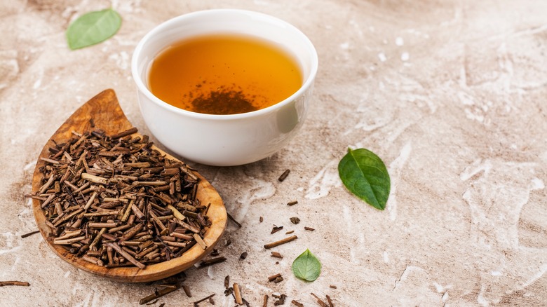 A bowl of hojicha tea next to hojicha tea leaves