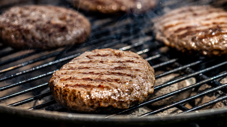 Several burger patties on the grill.