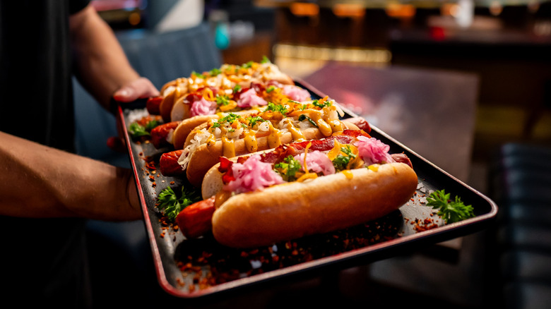 Tray of hot dogs topped with many garnishes.