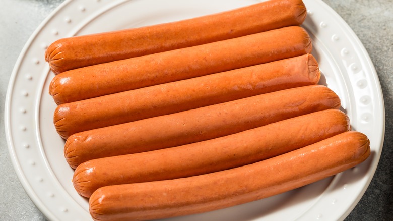 Raw hot dogs on white plate