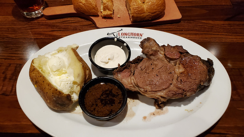 A steak and baked potato on a LongHorn Steakhouse plate.