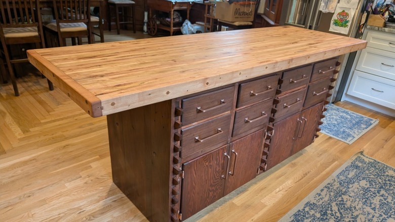 An old, wooden workbench repurposed into a kitchen island with a butcher block countertop