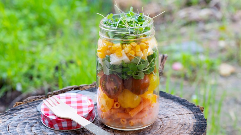 Pasta salad ingredients layered in a jar