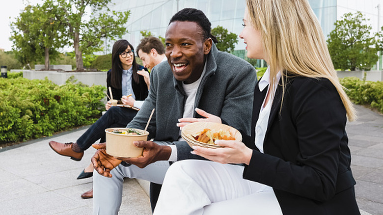 Business people eating takeout outside.