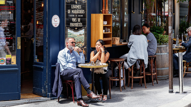 Parisians and tourists eating and drinking on the terrace of the traditional outdoor Parisian bistro Le Bon Georges.
