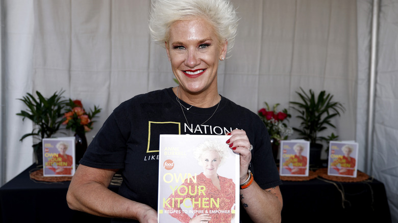 Anne Burrell posing with her cookbook 'Own Your Kitchen'