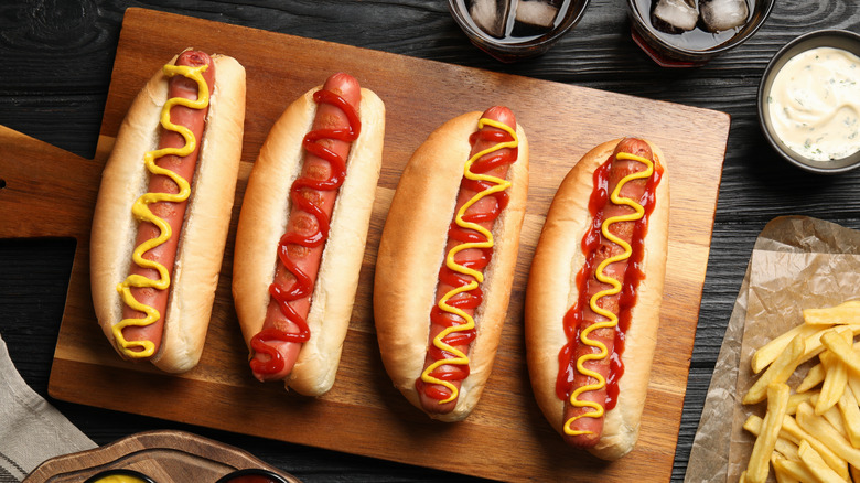 four hot dogs on a wooden cutting board