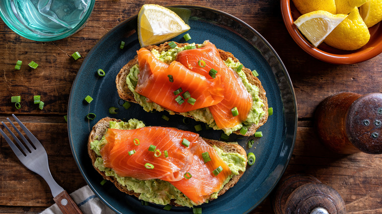 Two pieces of avocado toast topped with smoked salmon and chives.