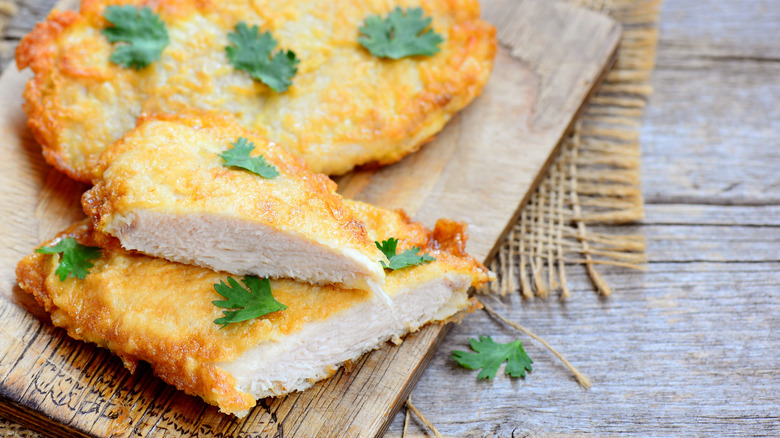 breaded chicken breast displayed on wooden board