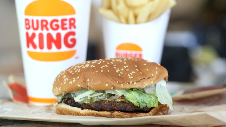 A Burger King Whopper with a drink and fries in the background