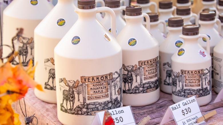 A variety of Vermont maple syrup jugs sit on a table outside
