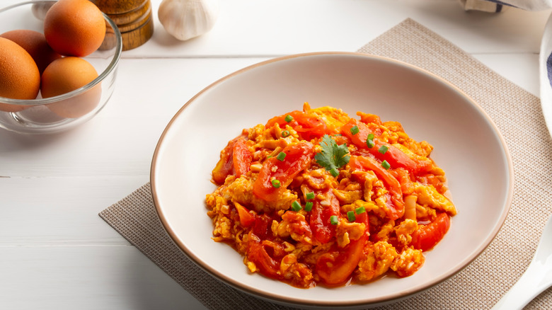 Scrambled eggs with tomatoes and peppers, topped with chives and parsley leaf
