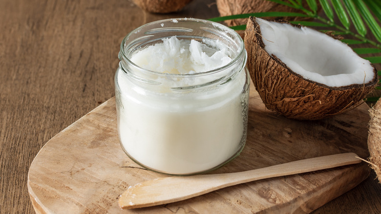 coconut butter in jar next to wooden spoon