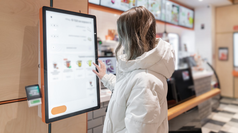 Woman ordering off of screen at fast food.