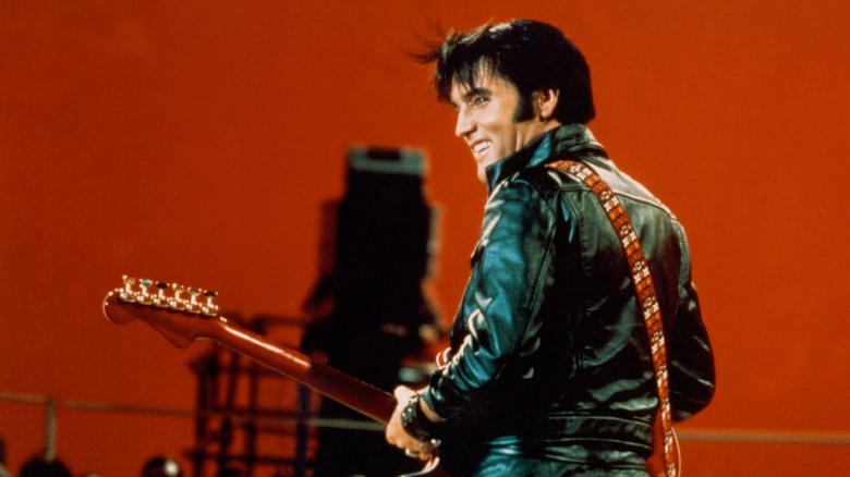 Profile view of Elvis Presley playing the guitar.