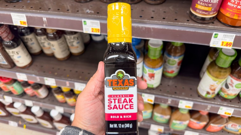 Customer holding Texas Roadhouse steak sauce in store aisle