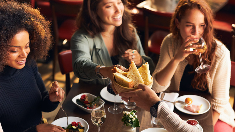 Women dining at a restaurant passing bread basket