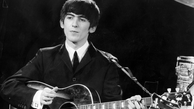 Black-and-white photo of George Harrison playing a guitar