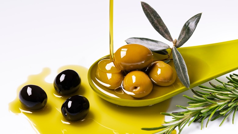 olive oil drizzle onto olives and rosemary